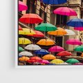Obraz w ramie 80x80 - Barwna symfonia wyobraźni - fotografia, kolorowe parasolki podwieszone nad ulicą - rama biała