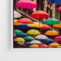 Obraz w ramie 70x50 - Barwna symfonia wyobraźni - fotografia, kolorowe parasolki podwieszone nad ulicą - rama biała