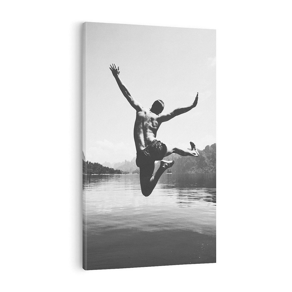 Obraz na płótnie 50x70 - Beztroska Chwila - czarno biała fotografia, mężczyzna wesoło wskakuje do keziora w górach
