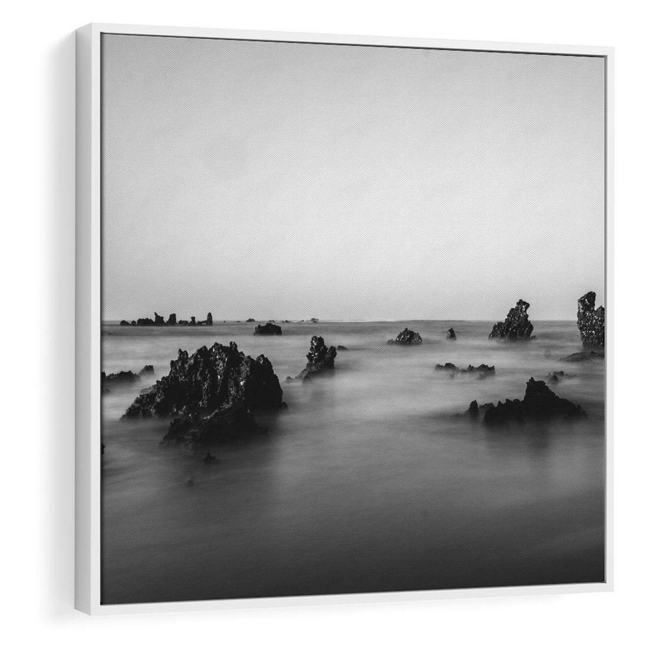 Obraz w ramie 50x50 - Harmonia świateł i cieni - zamglona dzika plaża, skały na plaży - rama biała