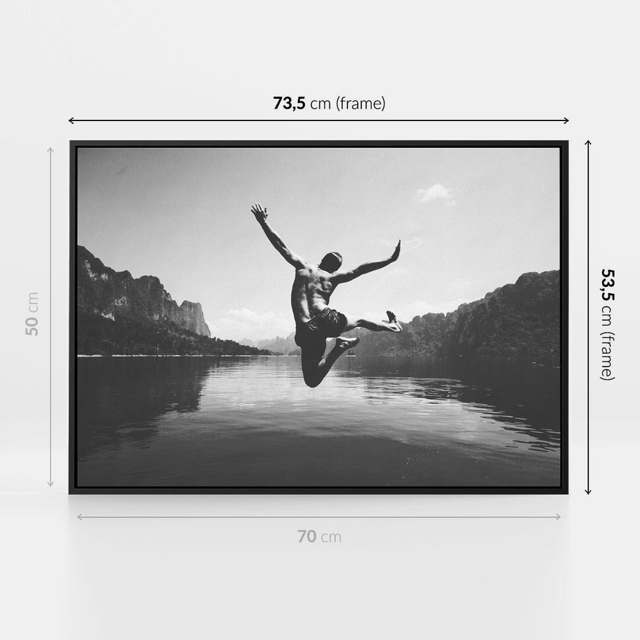 Obraz w ramie 70x50 - Beztroska Chwila - czarno biała fotografia, mężczyzna wesoło wskakuje do keziora w górach - rama czarna