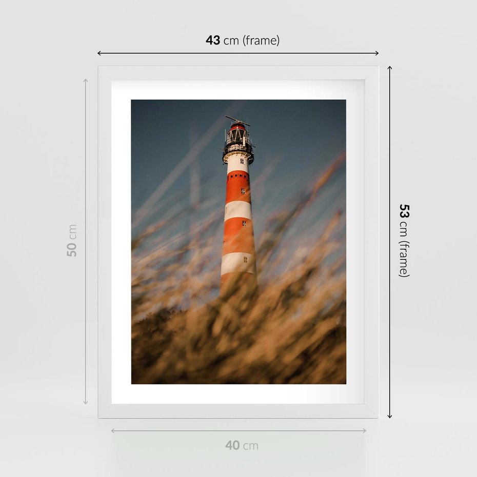 Plakat w ramie 40x50 - Magia nadmorskiego światła - latarnia morska, ujęcie z za trawy - rama biała