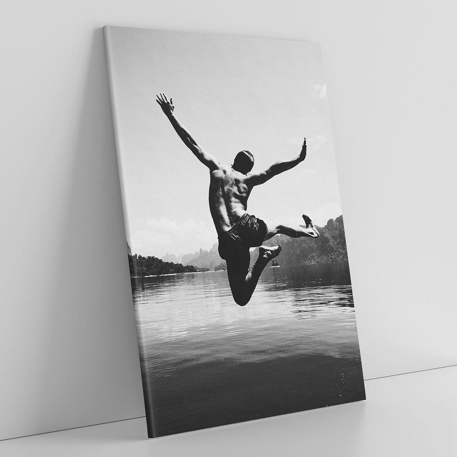 Obraz na płótnie 50x70 - Beztroska Chwila - czarno biała fotografia, mężczyzna wesoło wskakuje do keziora w górach