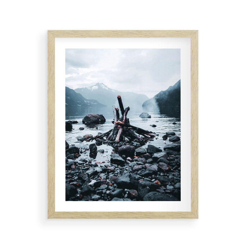 Plakat w ramie 40x50 - To ujęcie jeziora w górach z zgaszonym ogniskiem nad brzegiem, tworząc atmosferę spokoju i refleksji w otoczeniu przyrody. - jezioro w górach, zgaszone ognisko - rama drewno