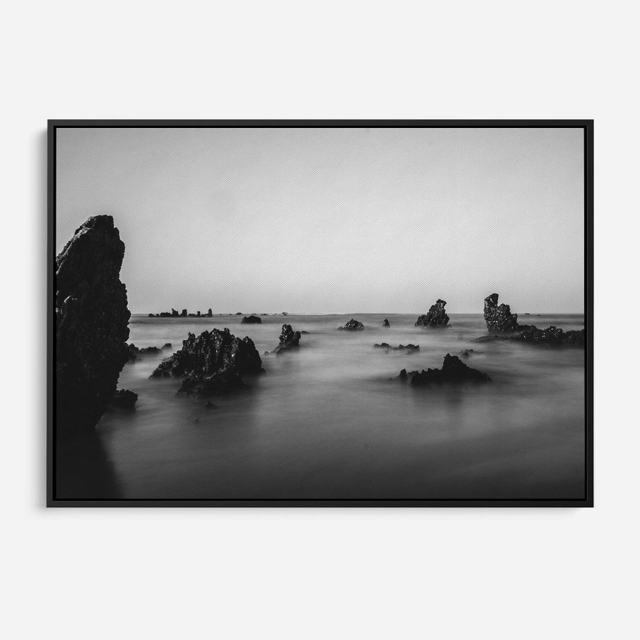 Obraz w ramie 70x50 - Harmonia świateł i cieni - zamglona dzika plaża, skały na plaży - rama czarna