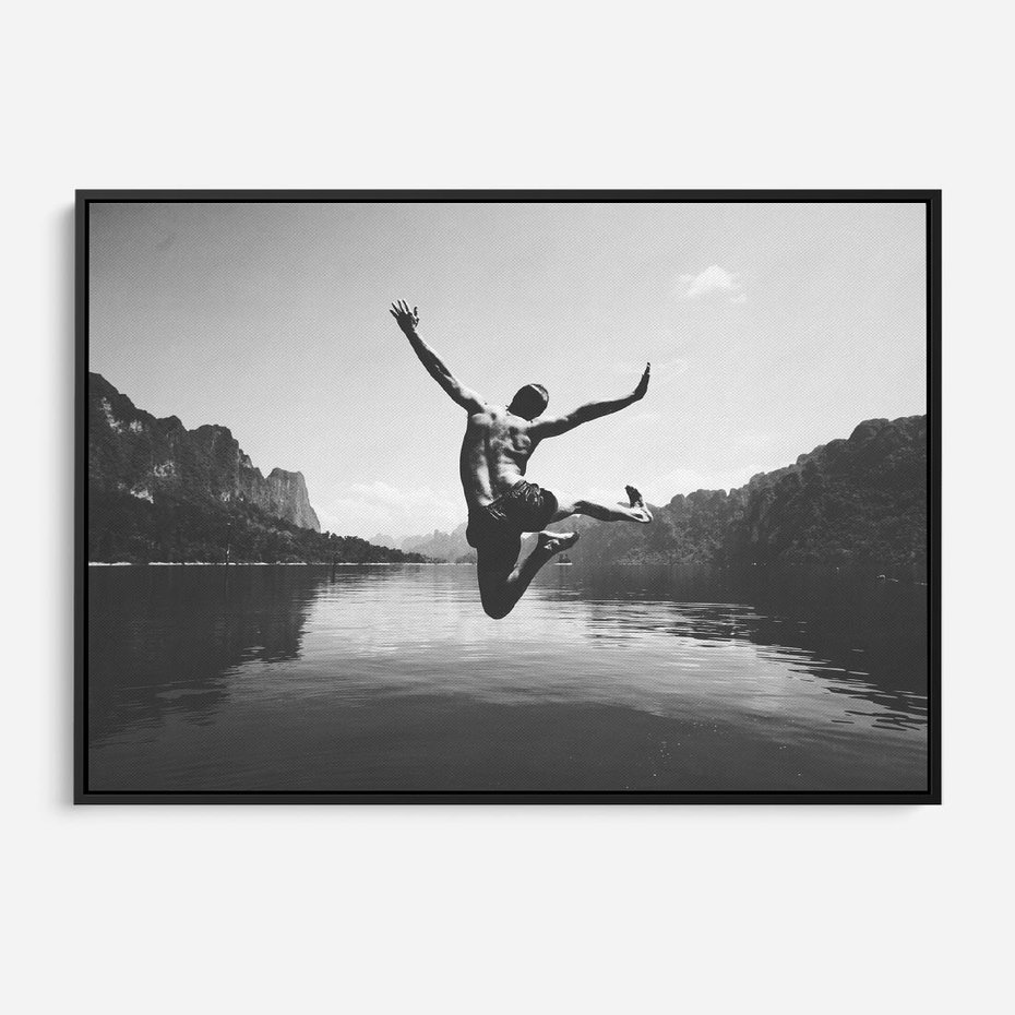Obraz w ramie 100x70 - Beztroska Chwila - czarno biała fotografia, mężczyzna wesoło wskakuje do keziora w górach - rama czarna