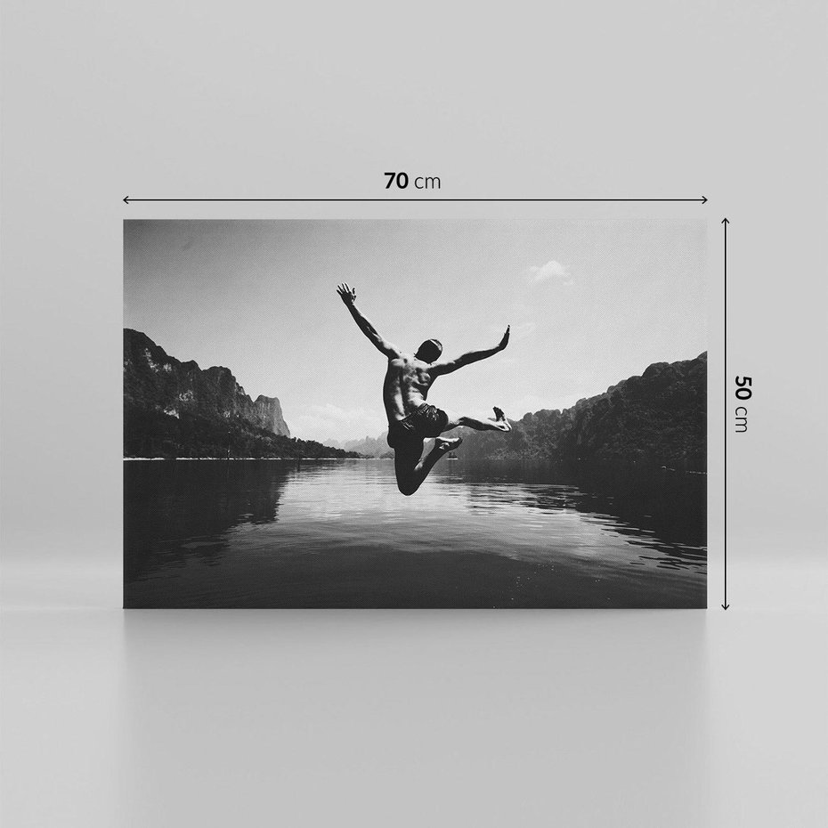 Obraz na płótnie 70x50 - Beztroska Chwila - czarno biała fotografia, mężczyzna wesoło wskakuje do keziora w górach