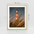 Plakat w ramie 40x50 - Magia nadmorskiego światła - latarnia morska, ujęcie z za trawy - rama drewno