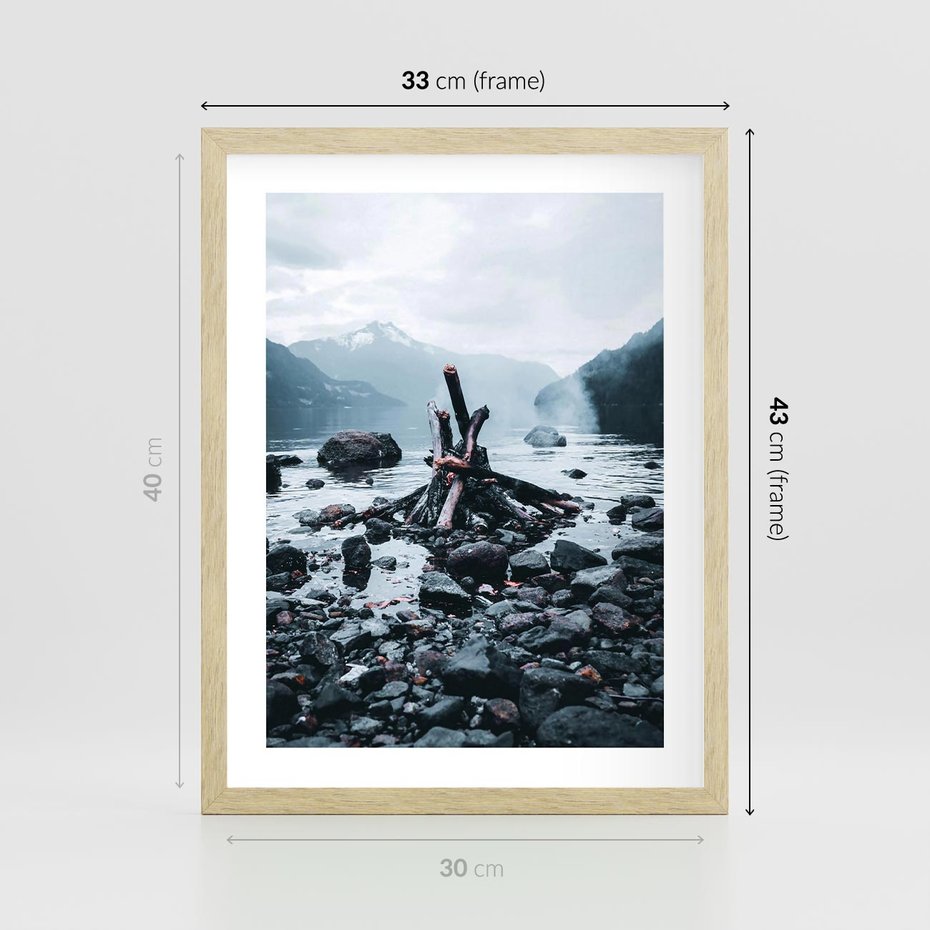 Plakat w ramie 30x40 - To ujęcie jeziora w górach z zgaszonym ogniskiem nad brzegiem, tworząc atmosferę spokoju i refleksji w otoczeniu przyrody. - jezioro w górach, zgaszone ognisko - rama drewno