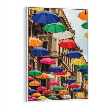 Obraz w ramie 80x120 - Barwna symfonia wyobraźni - fotografia, kolorowe parasolki podwieszone nad ulicą - rama biała