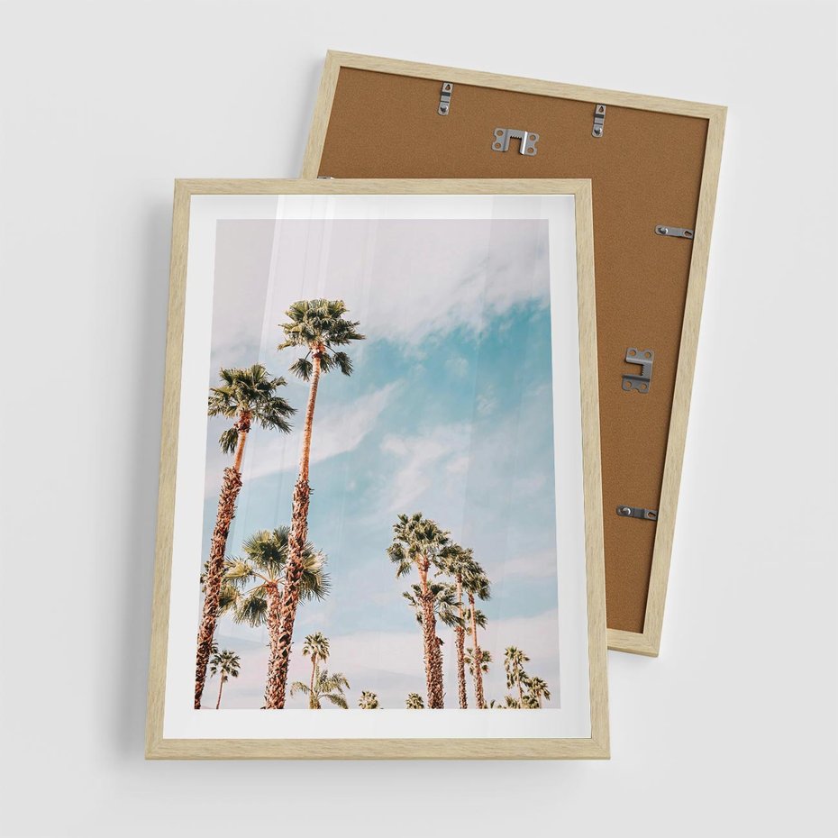 Plakat w ramie 50x70 - Tropikalna Sielskość: Palmy i Błękitne Niebo - palmy na tle błękitnego nieba - rama drewno