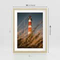 Plakat w ramie 30x40 - Magia nadmorskiego światła - latarnia morska, ujęcie z za trawy - rama drewno