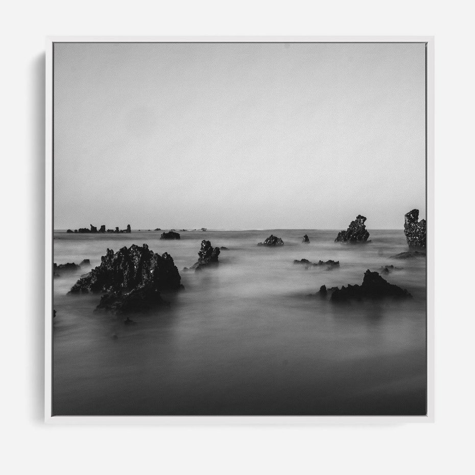 Obraz w ramie 80x80 - Harmonia świateł i cieni - zamglona dzika plaża, skały na plaży - rama biała