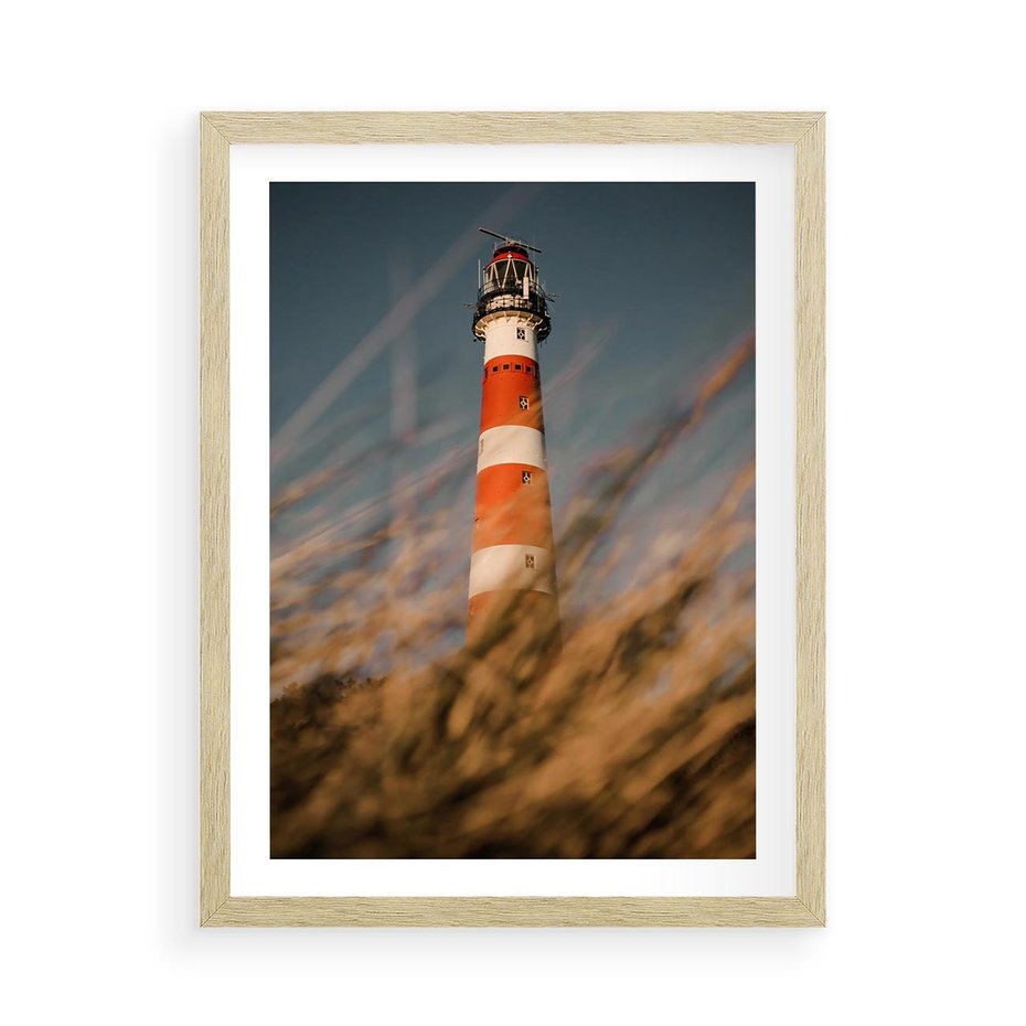 Plakat w ramie 50x70 - Magia nadmorskiego światła - latarnia morska, ujęcie z za trawy - rama drewno