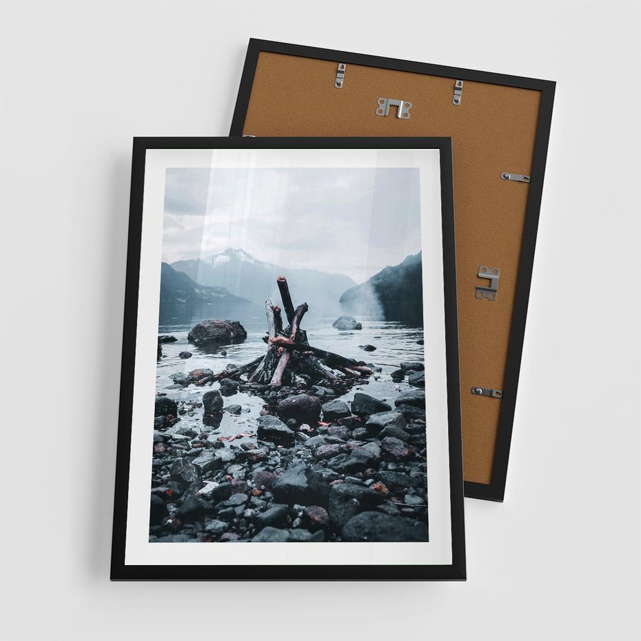 Plakat w ramie 50x70 - To ujęcie jeziora w górach z zgaszonym ogniskiem nad brzegiem, tworząc atmosferę spokoju i refleksji w otoczeniu przyrody. - jezioro w górach, zgaszone ognisko - rama czarna