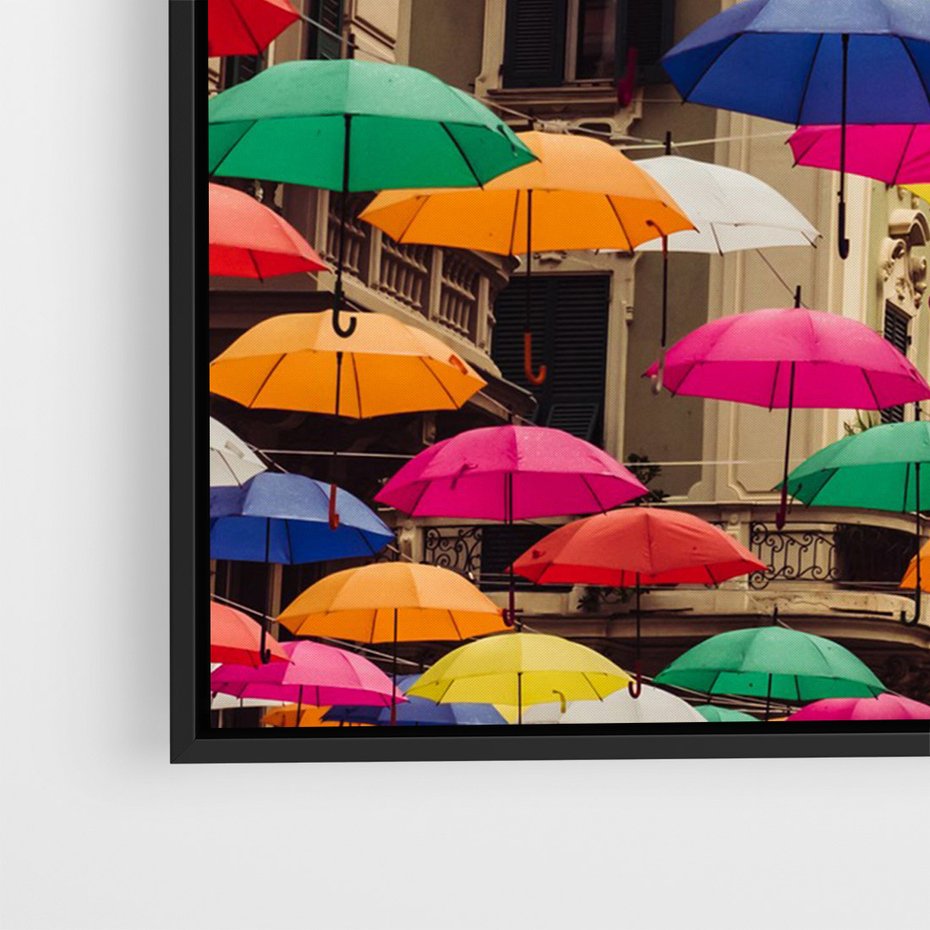 Obraz w ramie 70x100 - Barwna symfonia wyobraźni - fotografia, kolorowe parasolki podwieszone nad ulicą - rama czarna
