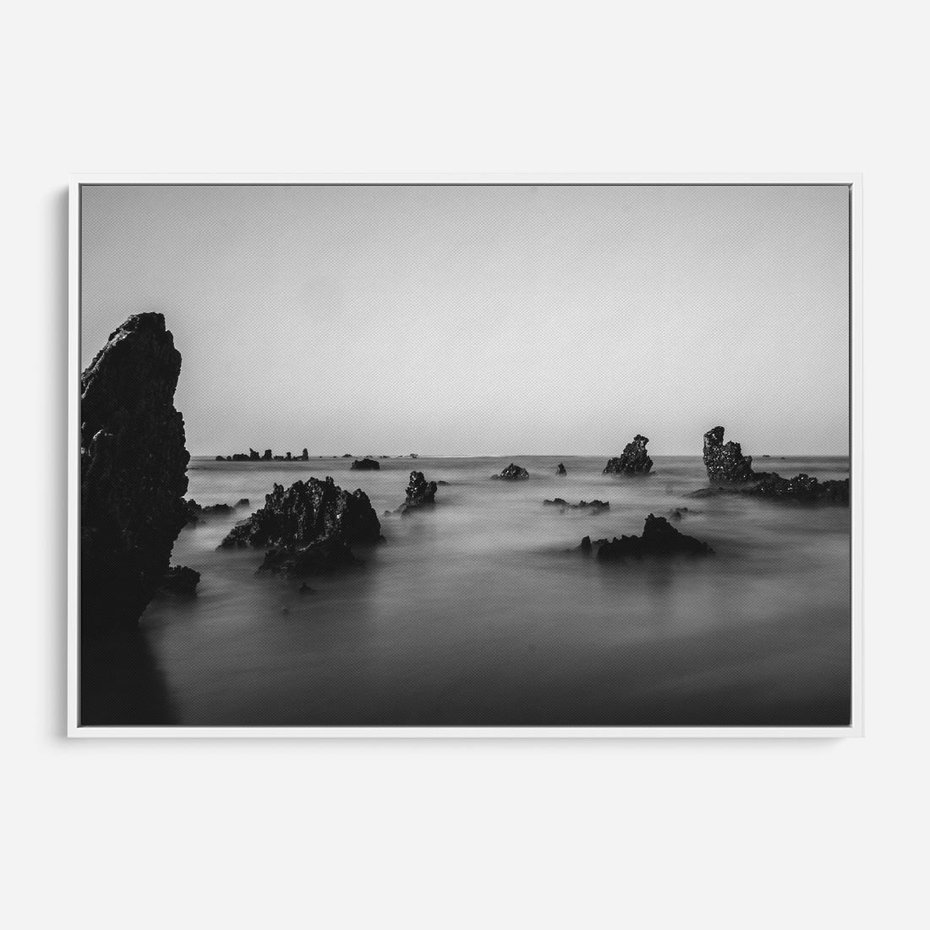 Obraz w ramie 100x70 - Harmonia świateł i cieni - zamglona dzika plaża, skały na plaży - rama biała