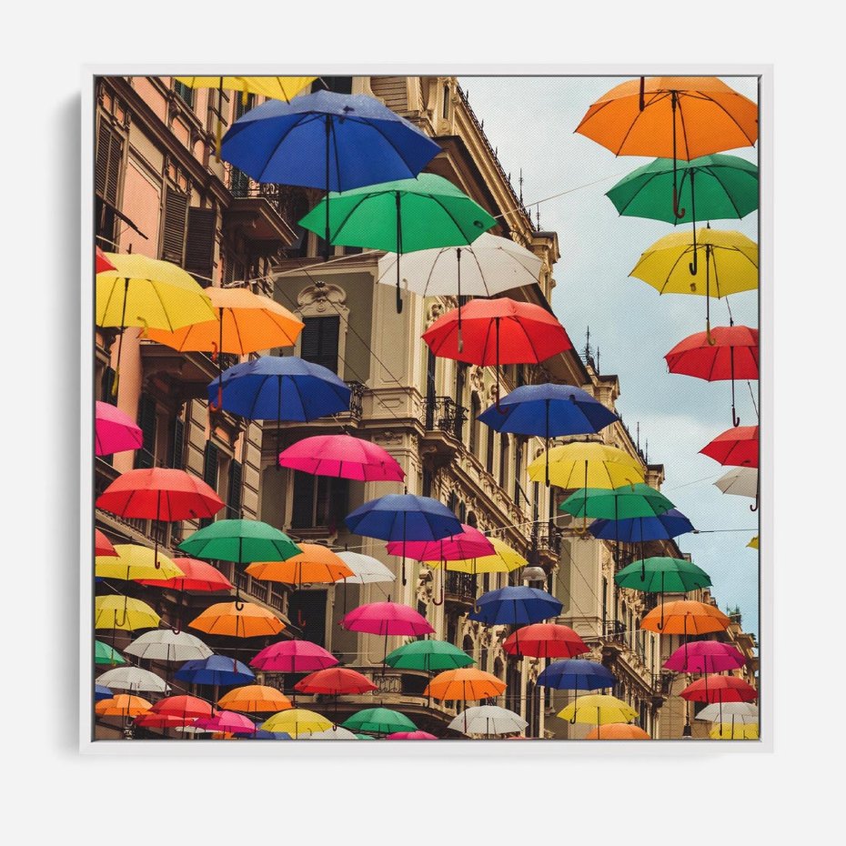 Obraz w ramie 50x50 - Barwna symfonia wyobraźni - fotografia, kolorowe parasolki podwieszone nad ulicą - rama biała