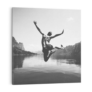 Obraz na płótnie 40x40 - Beztroska Chwila - czarno biała fotografia, mężczyzna wesoło wskakuje do keziora w górach