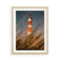 Plakat w ramie 50x70 - Magia nadmorskiego światła - latarnia morska, ujęcie z za trawy - rama drewno