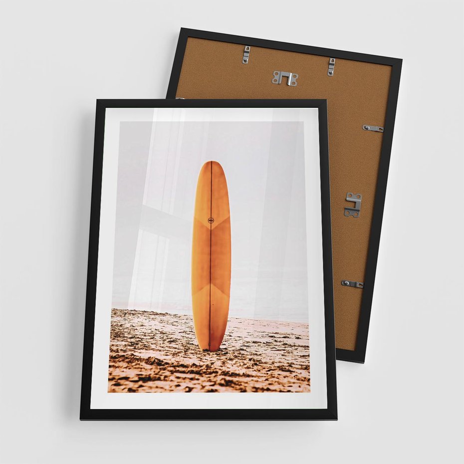 Plakat w ramie 50x70 - Deska w Piasku: Gotowa na Fale - plaża, pomarańczowa deska surfingowa wbita w piasek - rama czarna