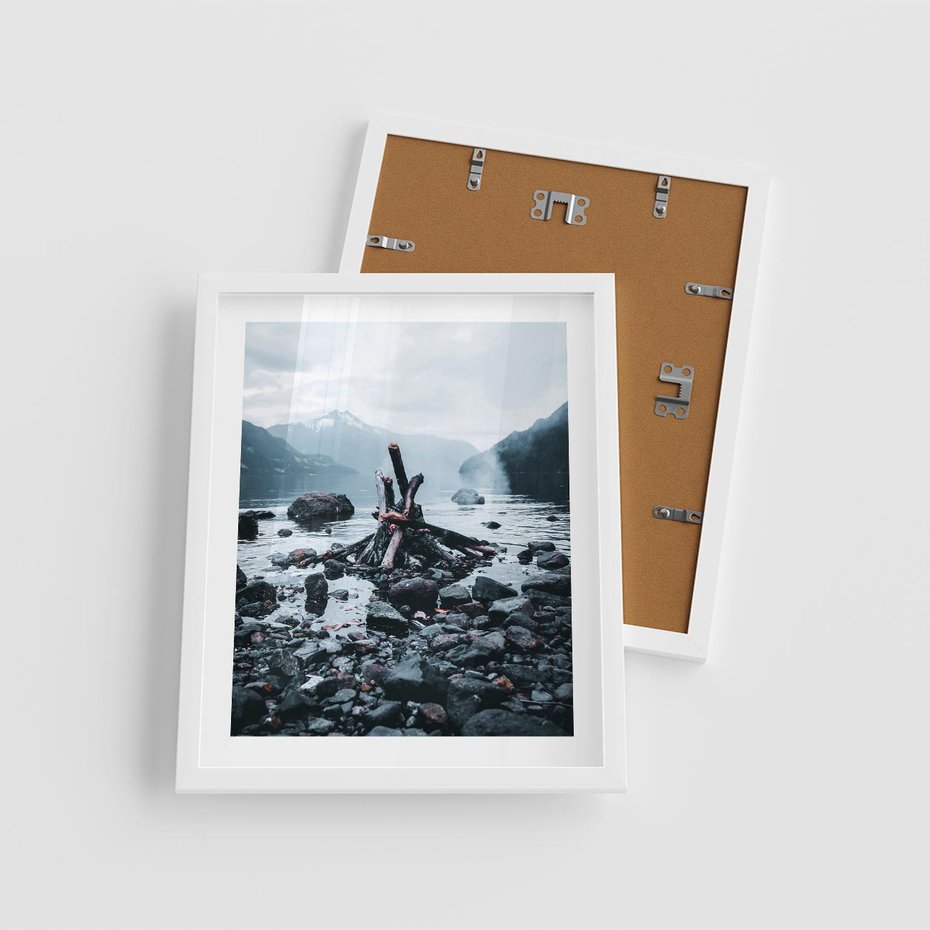 Plakat w ramie 40x50 - To ujęcie jeziora w górach z zgaszonym ogniskiem nad brzegiem, tworząc atmosferę spokoju i refleksji w otoczeniu przyrody. - jezioro w górach, zgaszone ognisko - rama biała