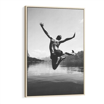Obraz w ramie 80x120 - Beztroska Chwila - czarno biała fotografia, mężczyzna wesoło wskakuje do keziora w górach - rama drewno