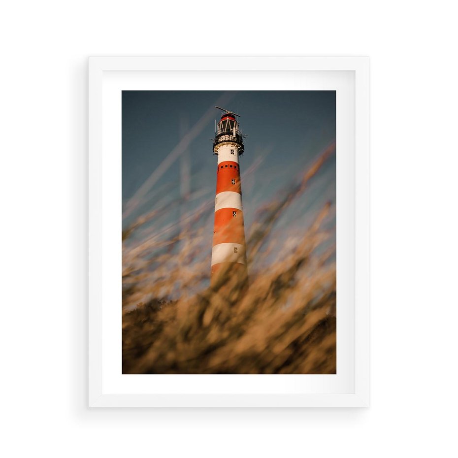 Plakat w ramie 40x50 - Magia nadmorskiego światła - latarnia morska, ujęcie z za trawy - rama biała