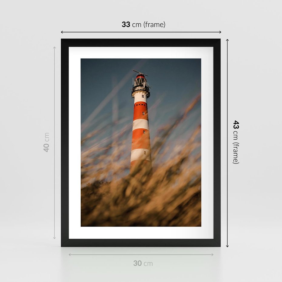 Plakat w ramie 30x40 - Magia nadmorskiego światła - latarnia morska, ujęcie z za trawy - rama czarna