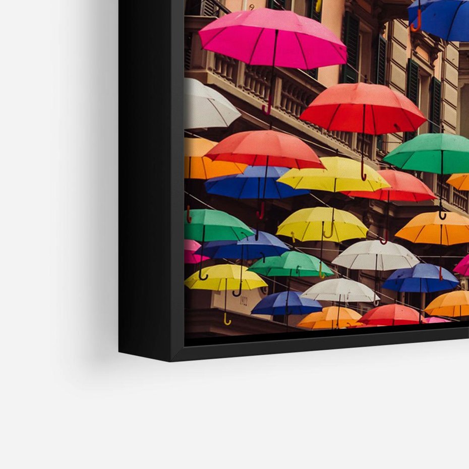 Obraz w ramie 100x70 - Barwna symfonia wyobraźni - fotografia, kolorowe parasolki podwieszone nad ulicą - rama czarna