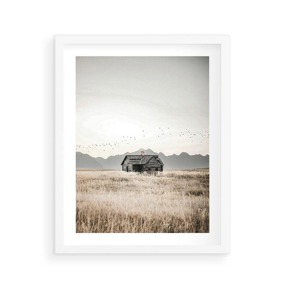 Plakat w ramie 40x50 - Wiejska Idylla - stary drewniany dom w polu suchej trawy, fotografia - rama biała