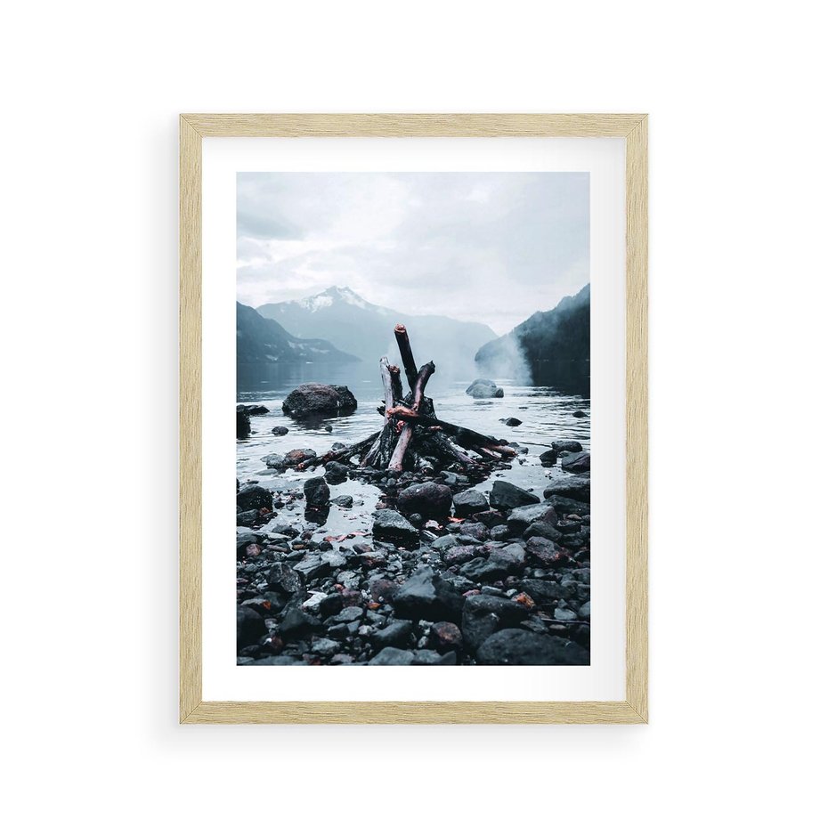 Plakat w ramie 30x40 - To ujęcie jeziora w górach z zgaszonym ogniskiem nad brzegiem, tworząc atmosferę spokoju i refleksji w otoczeniu przyrody. - jezioro w górach, zgaszone ognisko - rama drewno