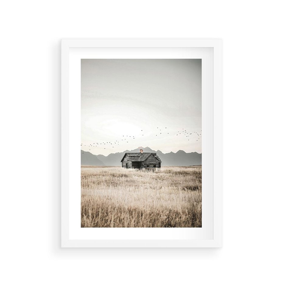 Plakat w ramie 30x40 - Wiejska Idylla - stary drewniany dom w polu suchej trawy, fotografia - rama biała