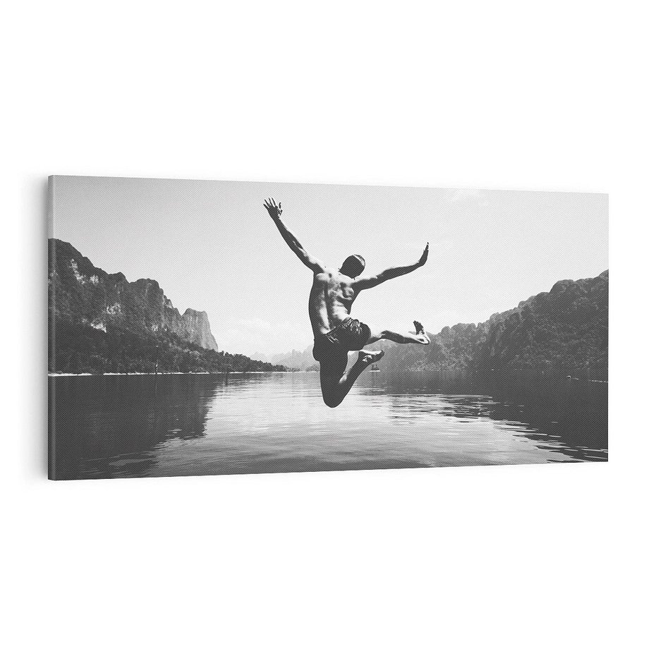 Obraz na płótnie 120x60 - Beztroska Chwila - czarno biała fotografia, mężczyzna wesoło wskakuje do keziora w górach