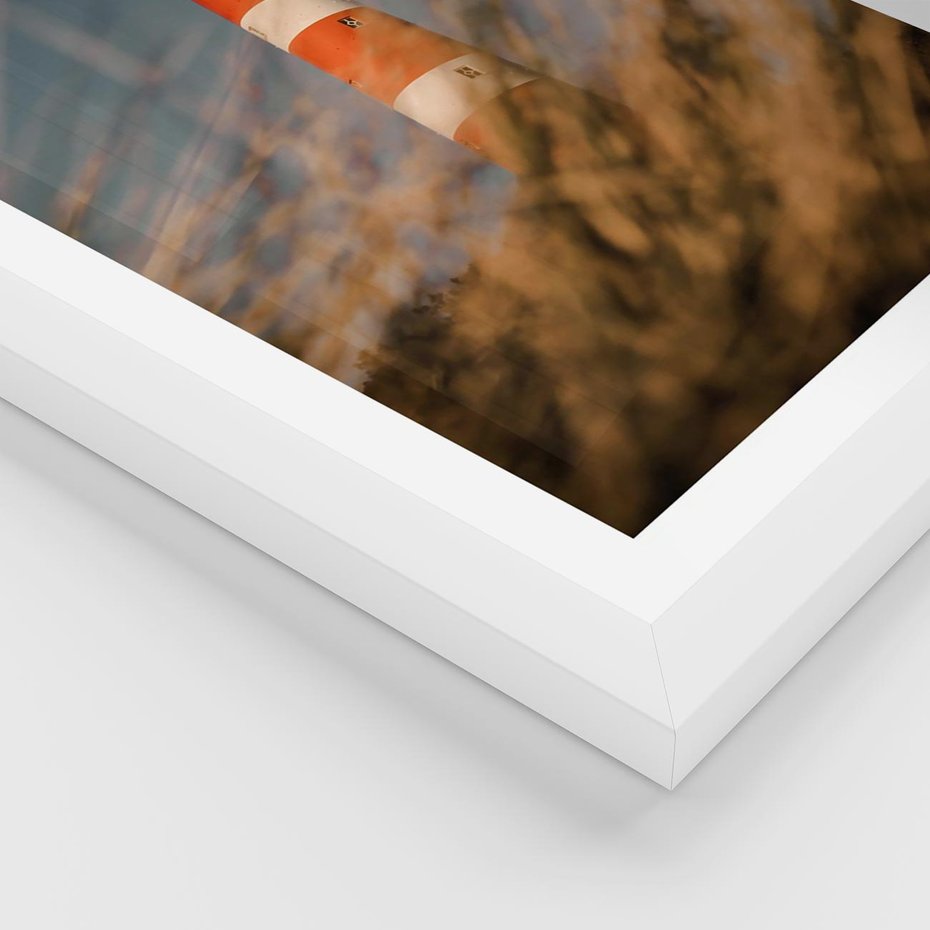 Plakat w ramie 30x40 - Magia nadmorskiego światła - latarnia morska, ujęcie z za trawy - rama biała