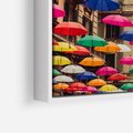 Obraz w ramie 50x50 - Barwna symfonia wyobraźni - fotografia, kolorowe parasolki podwieszone nad ulicą - rama biała