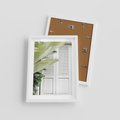 Plakat w ramie 30x40 - Tropikalne Okno - białe okiennice, zielona tropikalna roślina - rama biała