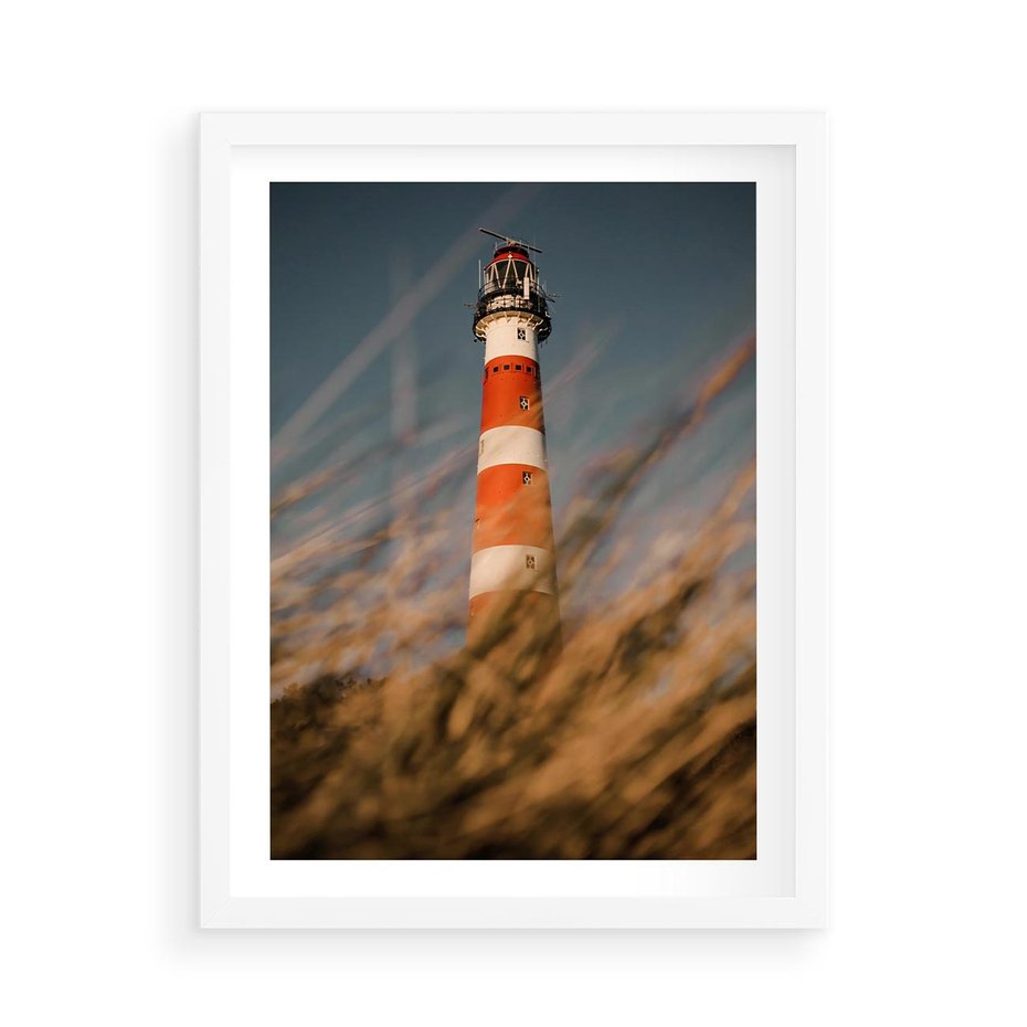 Plakat w ramie 50x70 - Magia nadmorskiego światła - latarnia morska, ujęcie z za trawy - rama biała