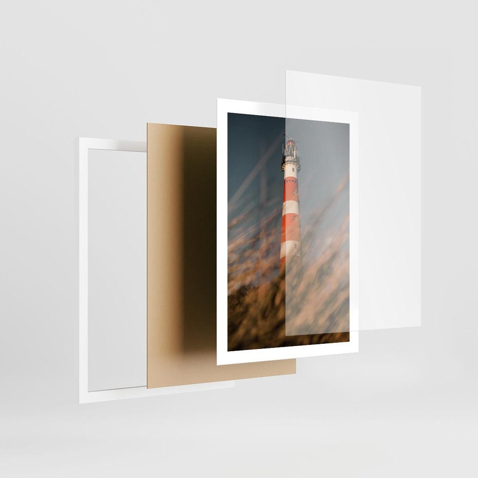 Plakat w ramie 50x70 - Magia nadmorskiego światła - latarnia morska, ujęcie z za trawy - rama biała
