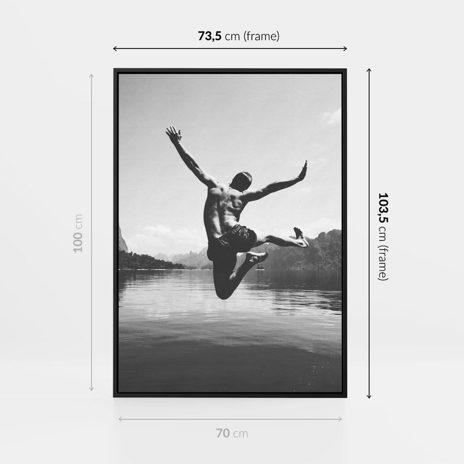 Obraz w ramie 70x100 - Beztroska Chwila - czarno biała fotografia, mężczyzna wesoło wskakuje do keziora w górach - rama czarna