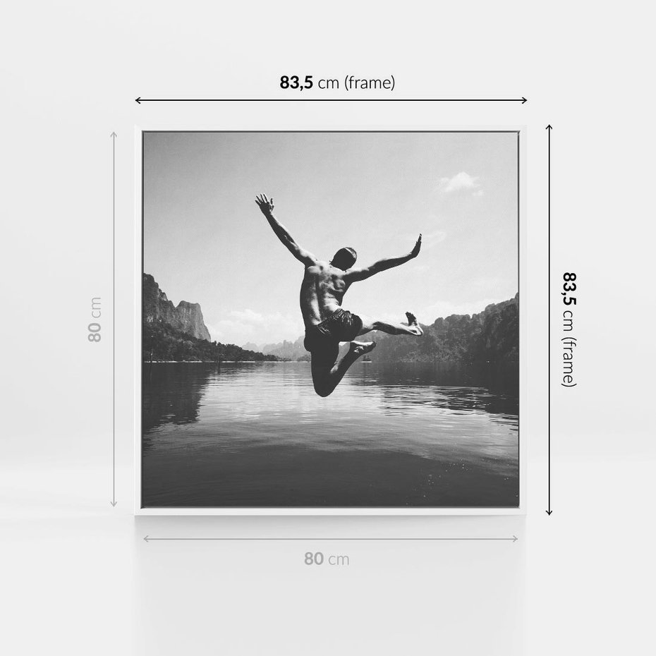 Obraz w ramie 80x80 - Beztroska Chwila - czarno biała fotografia, mężczyzna wesoło wskakuje do keziora w górach - rama biała
