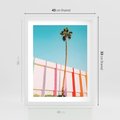 Plakat w ramie 40x50 - Tropikalny Kontrast - palma na tle błękitnego nieba, kolorowy mur - rama biała