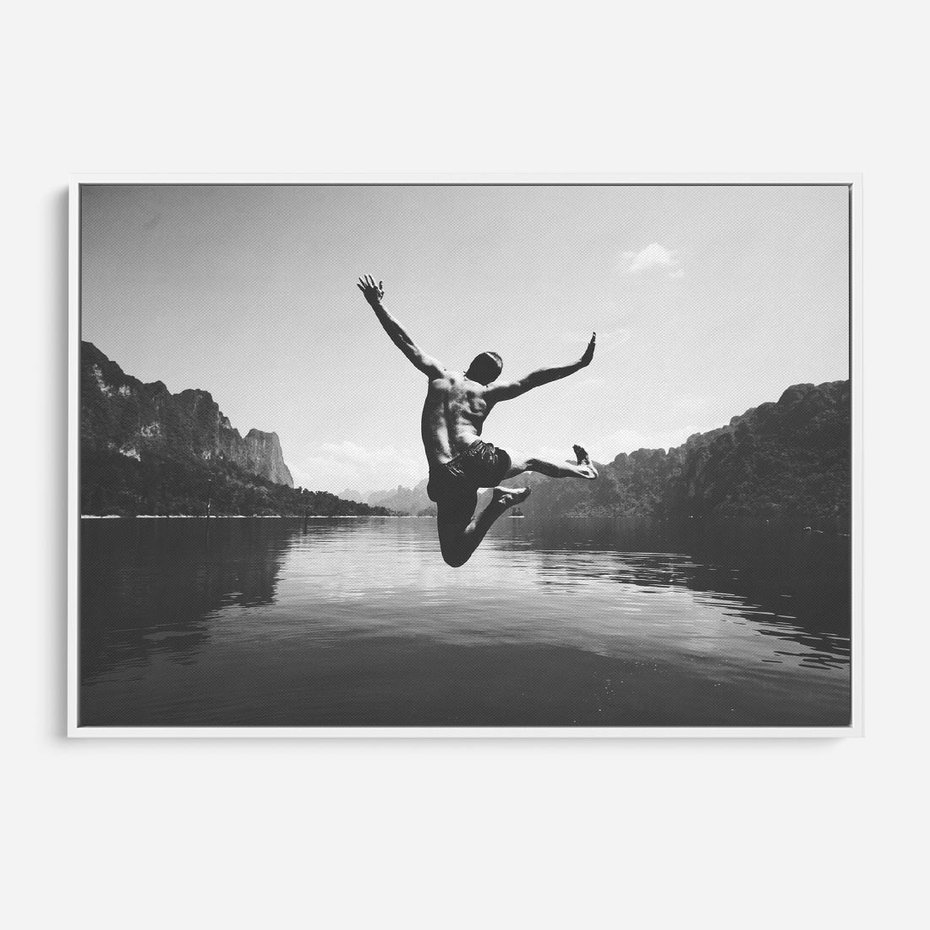 Obraz w ramie 120x80 - Beztroska Chwila - czarno biała fotografia, mężczyzna wesoło wskakuje do keziora w górach - rama biała