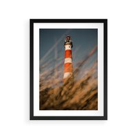 Plakat w ramie 50x70 - Magia nadmorskiego światła - latarnia morska, ujęcie z za trawy - rama czarna